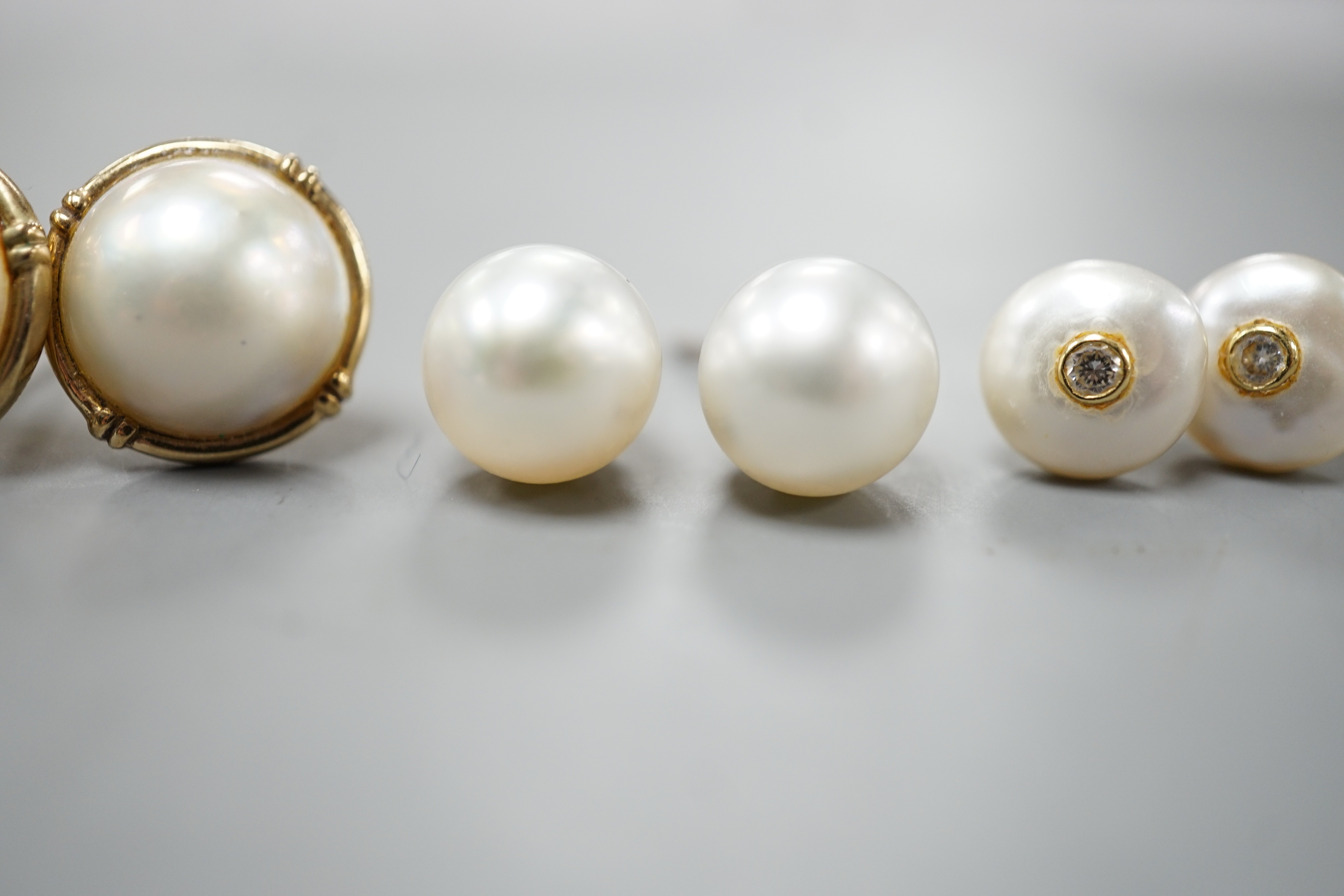 A pair of 18ct and cultured pear ear studs, a pair 9ct gold and mabe pearl ear studs and a pair of 18k, cultured pearl and diamond set ear studs (all lacking butterflies).